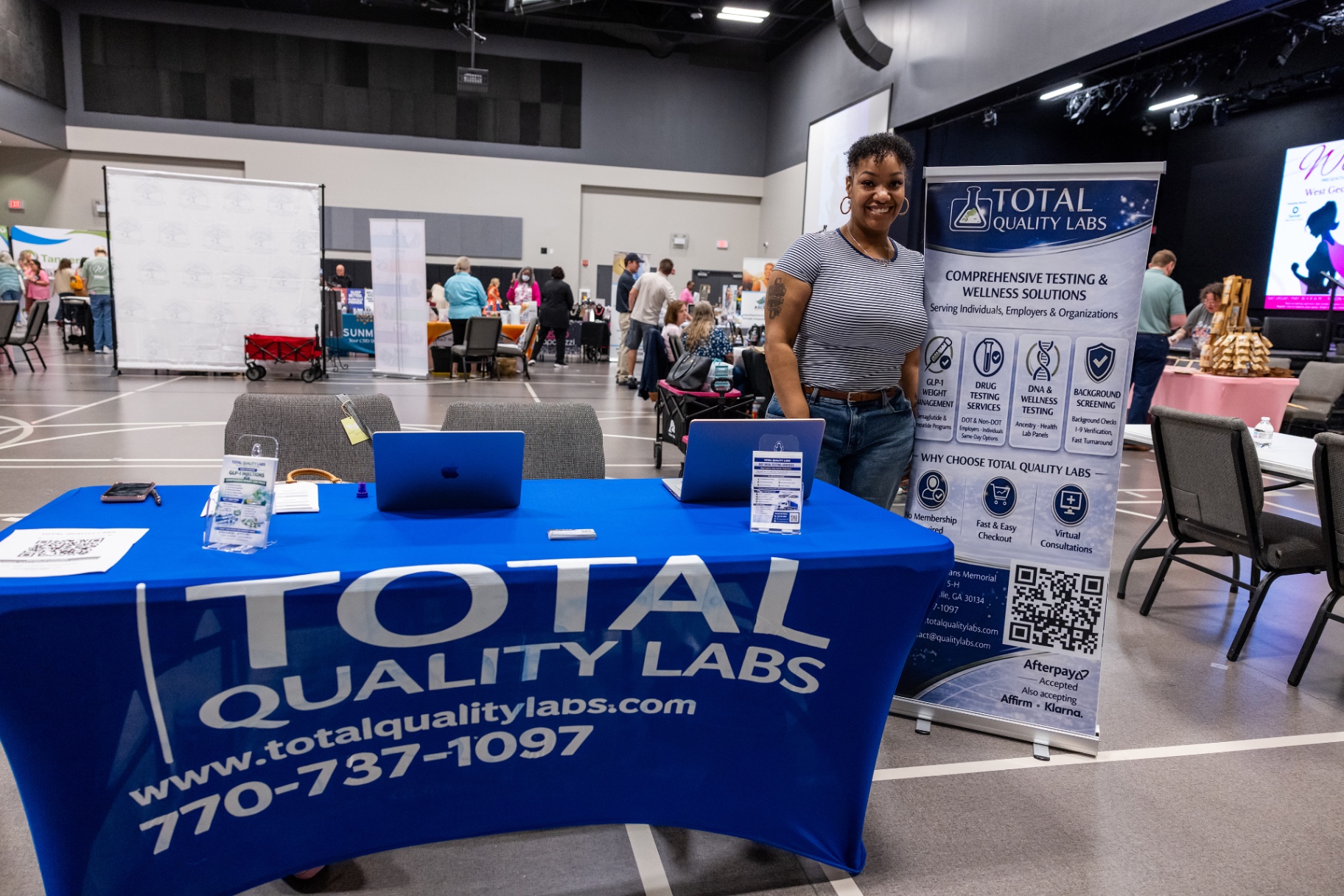 Kimi Cares partner at a Total Quality Labs booth during a community wellness networking event